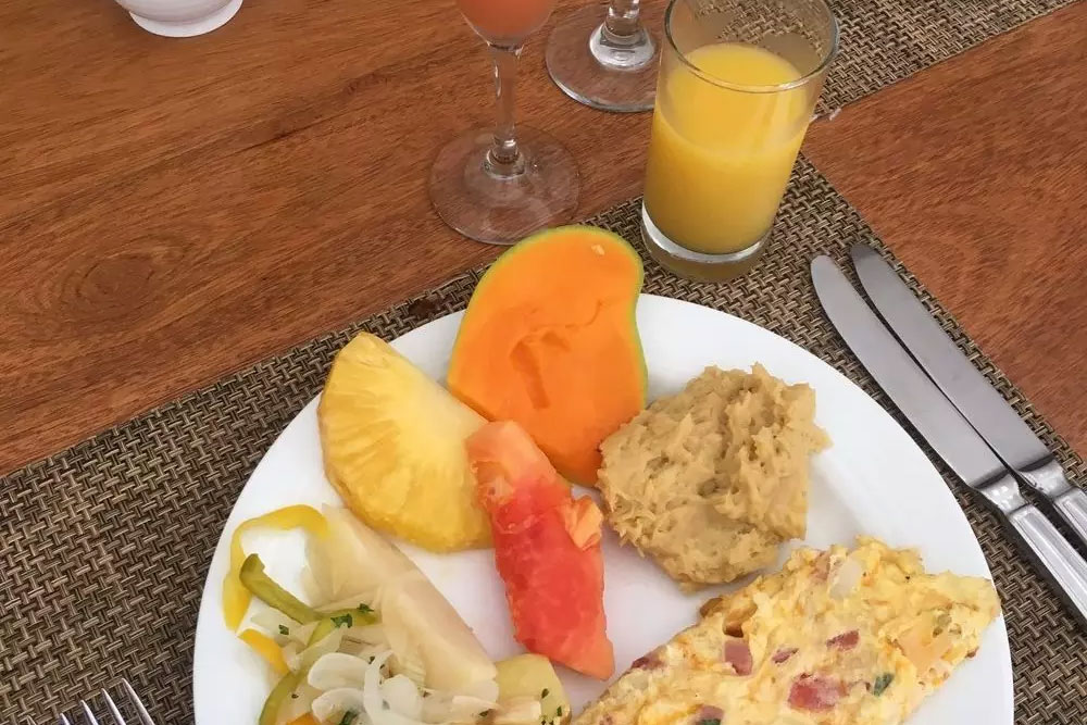 Delightful-Breakfast-Choices-In-The-Dominican-Republic-1000×675 A vibrant breakfast plate featuring fresh produce like pineapple and papaya, with a fluffy omelette and mashed potatoes, alongside orange juice, offering a healthy, nourishing start to the day.| Daré Vita Café | Las Vegas
