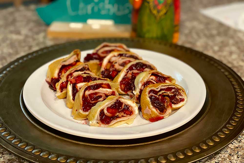 A white plate displays vibrant, rolled pastries filled with rich berry compote, highlighting the natural, fresh flavors of these wholesome, allergen-friendly treats, perfect for those seeking healthy living with minimal processing.| Daré Vita Café | Las Vegas