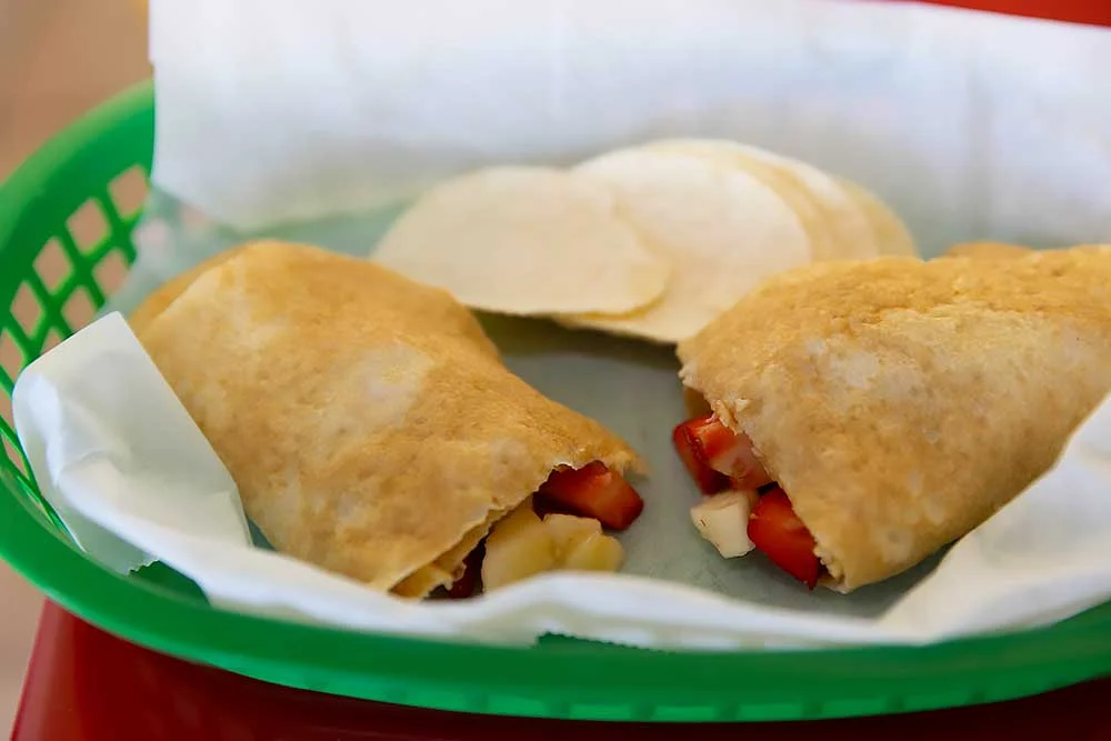 A green basket holds two gluten-free crepes filled with fresh strawberries and bananas, showcasing vibrant, natural ingredients, perfect for those seeking allergen-friendly, wholesome meals.| Daré Vita Café | Las Vegas