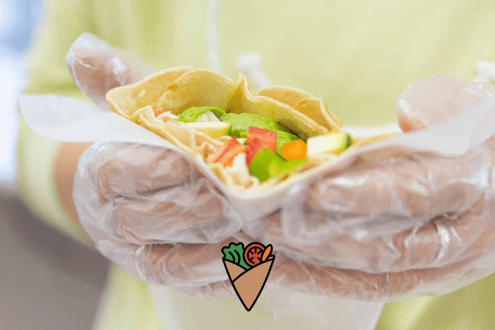 Understanding _Edible Grass Ingredient Free__ Why It’s Important for Your Health -2 A hand preparing a fresh vegetable wrap, highlighting healthy food choices at DareVitaCafe.