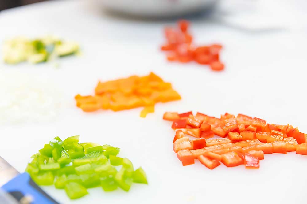 new-ingredients-1 Chopped fresh produce including vibrant green, red, and orange bell peppers on a white cutting board, emphasizing natural, wholesome ingredients ideal for healthy, allergen-friendly meals.| Daré Vita Café | Las Vegas