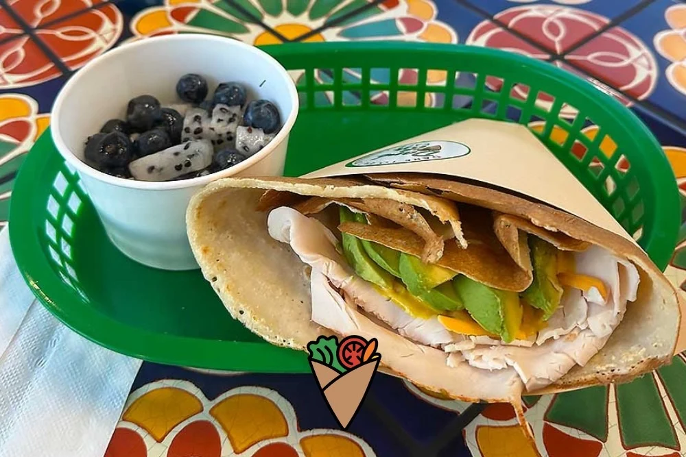 A New Kind of Comfort Food-2 A vibrant crepe filled with turkey, avocado, and fresh ingredients, served alongside a cup of blueberries and dragon fruit. This wholesome meal showcases Daré Vita Café's commitment to allergen-friendly, fresh flavors and healthy living.| Daré Vita Café | Las Vegas