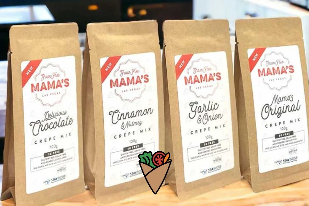 A New Kind of Comfort Food-3 Four brown bags of crepe mix labeled "Mama's Las Vegas" sit on a wooden counter, featuring flavors like chocolate and cinnamon. These allergen-friendly mixes are advertised as gluten-free and made with clean ingredients, ideal for healthy living.| Daré Vita Café | Las Vegas