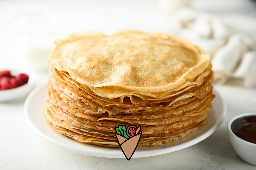 How Science and Nature Power Every Bite-3 A stack of golden-brown crepes on a white plate, surrounded by fresh raspberries and a bowl of chocolate sauce. These crepes are gluten-free and made with natural, clean ingredients, perfect for those seeking healthy, allergen-friendly options.| Daré Vita Café | Las Vegas