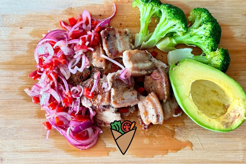 Behind the Apron_ The Heart and Vision of Dare Vita Café (4) A vibrant dish featuring fresh avocado, broccoli florets, and grilled meat, garnished with sliced red onions and bell peppers on a wooden board, perfect for those seeking allergen-friendly and nourishing meals.| Daré Vita Café | Las Vegas