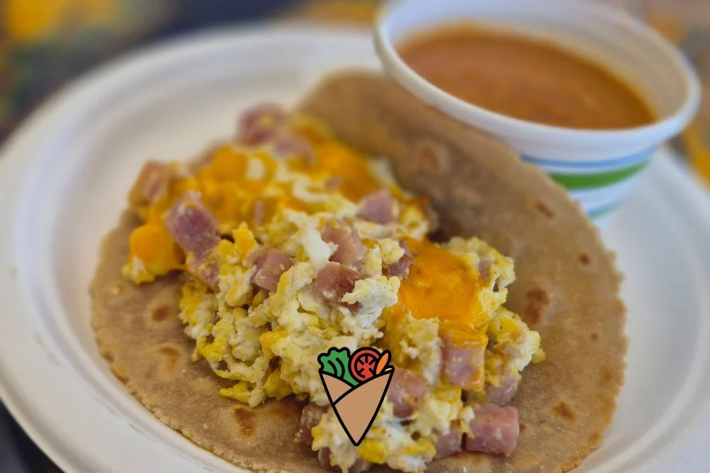 From Crêpe Fridays to Community_ How Food Brings Us Together (2) A wholesome meal of scrambled eggs with diced ham and melted cheese on a roti, served on a white plate with a bowl of soup. The dish showcases fresh flavors and minimal processing, emphasizing natural, clean ingredients for healthy living.| Daré Vita Café | Las Vegas